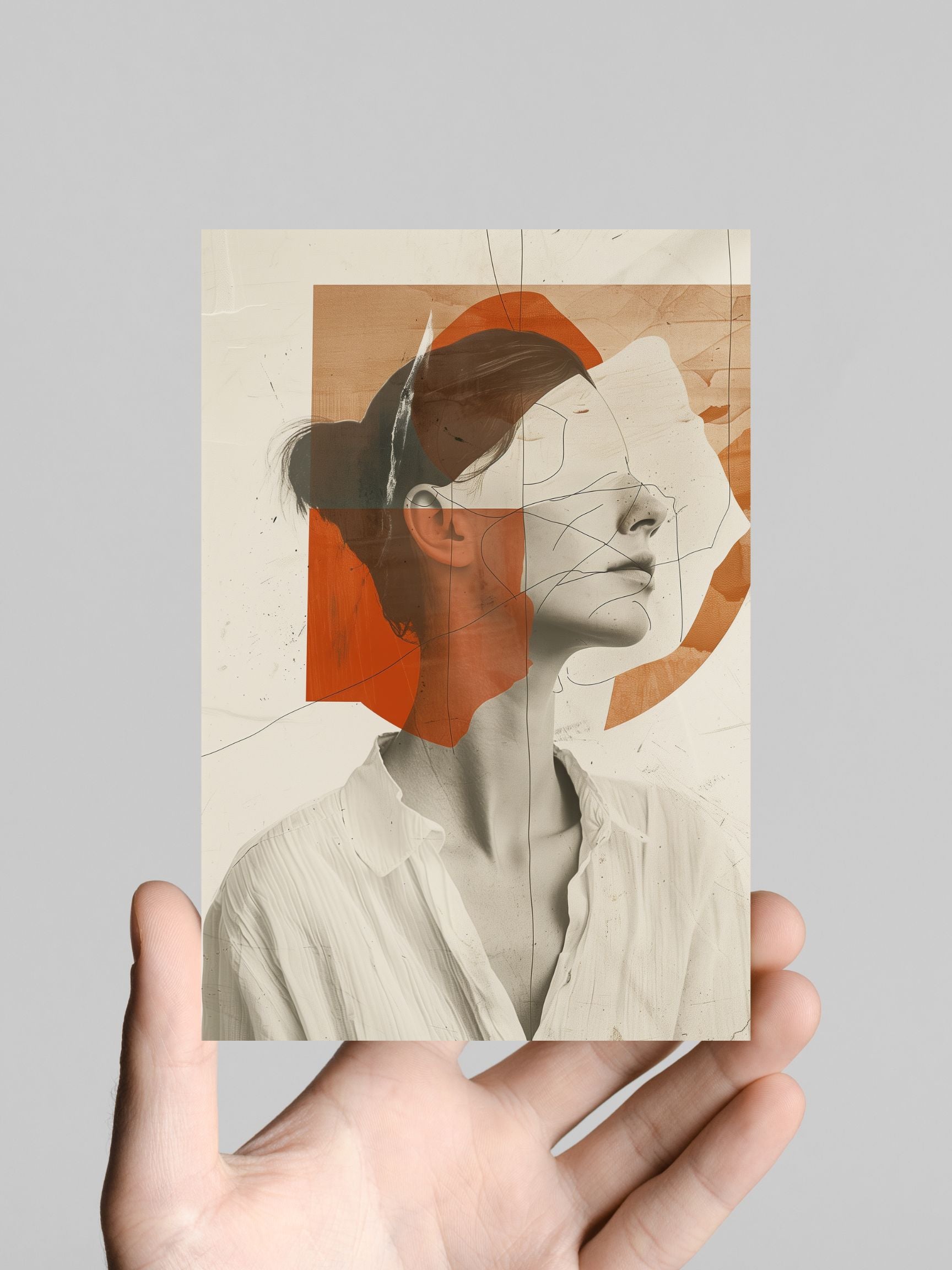 Hand holding abstract minimalist poster with terracotta tones and modern face line art, neutral background.