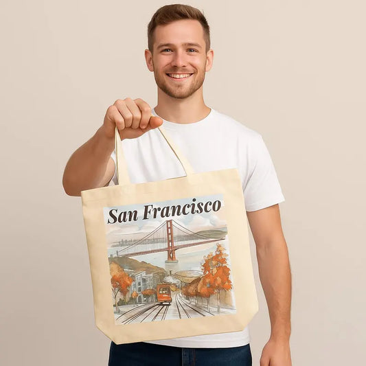 Man holding a beige canvas tote bag with a San Francisco print and smiling at the camera